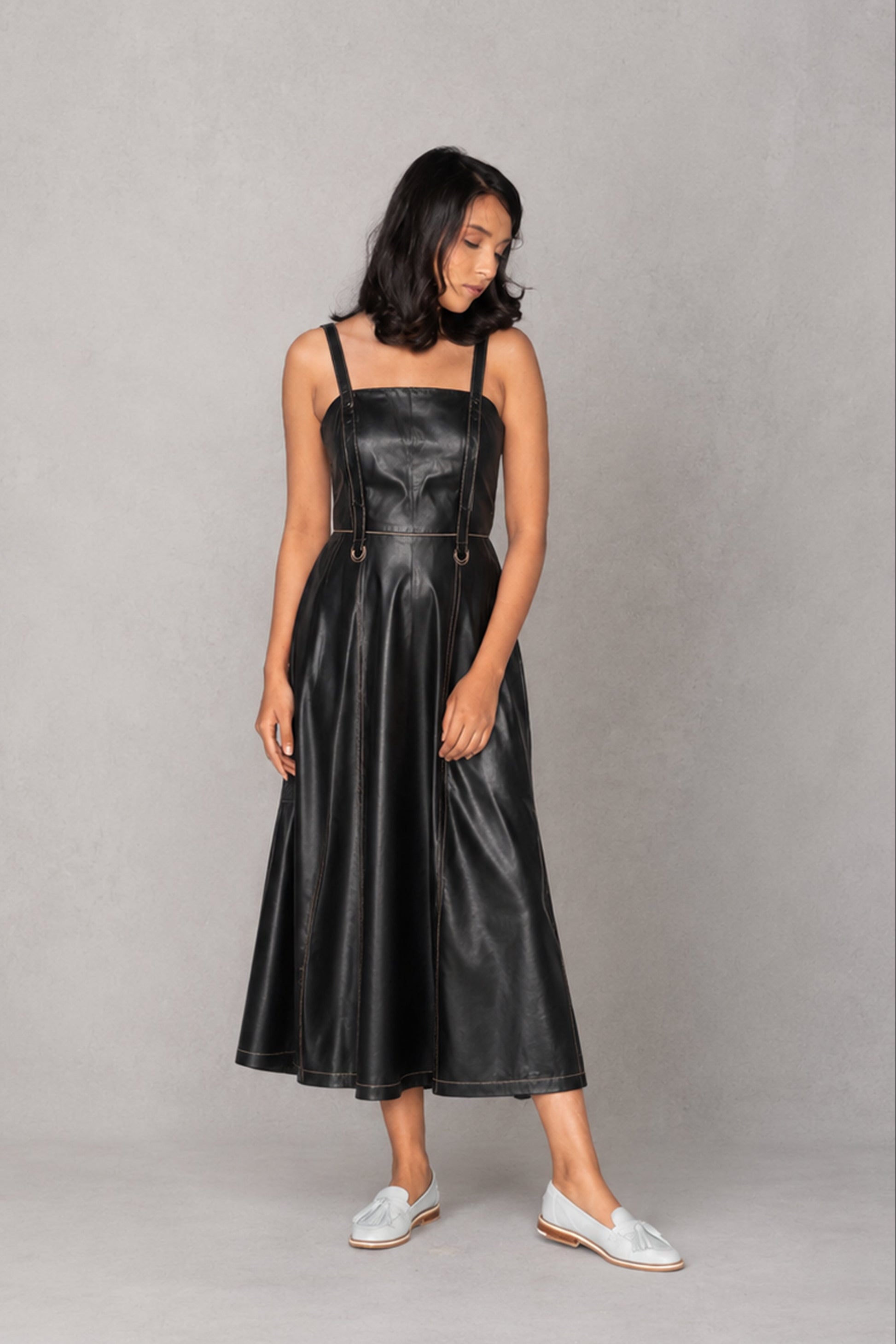 Woman wearing a black leather dress against a gray background