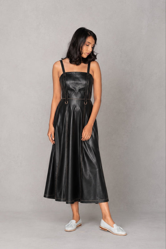 Woman wearing a black leather dress against a gray background