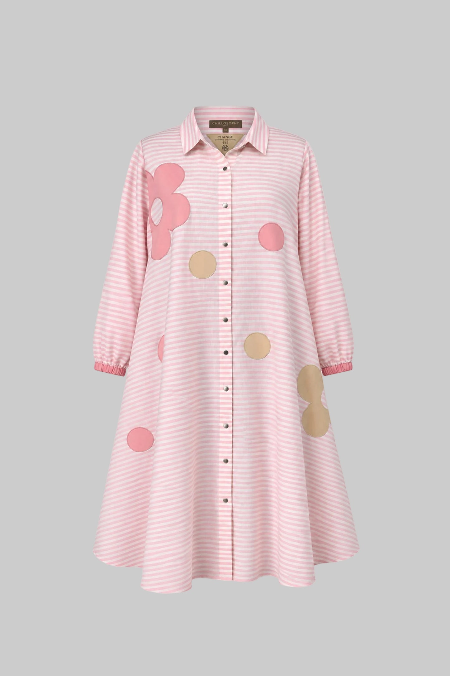 Pink striped dress with floral and polka dot patches on a gray background