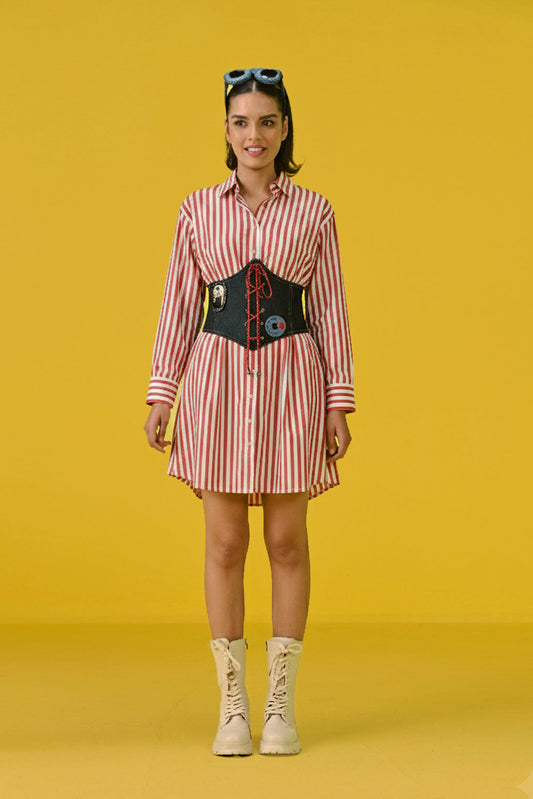 Woman wearing a striped dress with a belt and boots on a yellow background