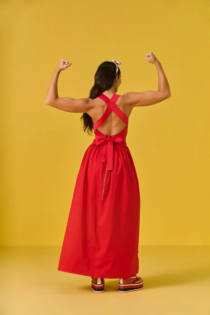 Woman in a red dress flexing her muscles against a yellow background