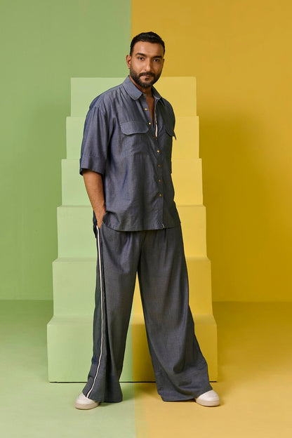 Man in a gray outfit standing against a colorful geometric background