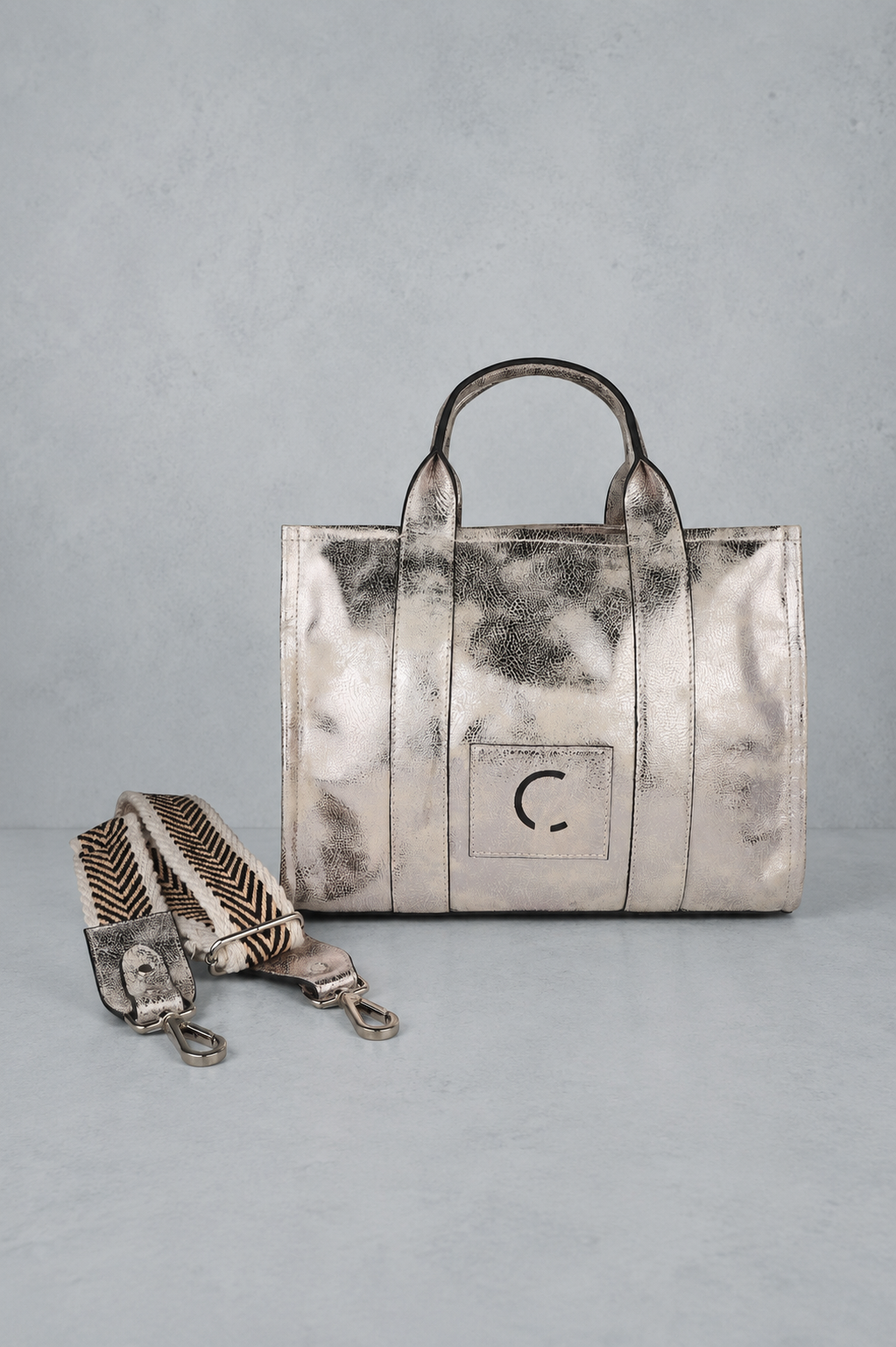 Silver handbag with a strap on a gray background