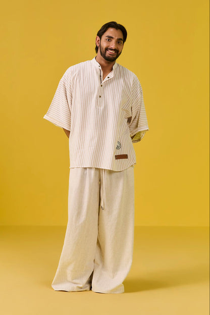 Man wearing a beige outfit against a yellow background