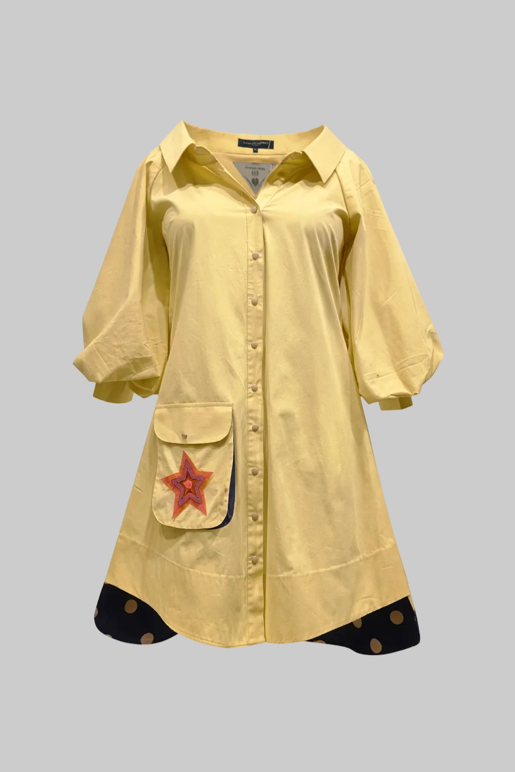 Yellow shirt dress with a red star patch on a light gray background