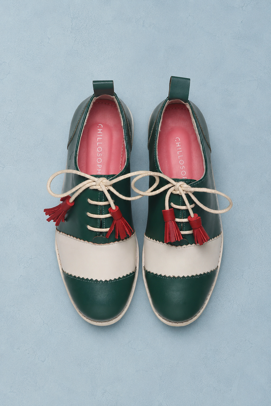 Green and white shoes with red tassels on a light blue background